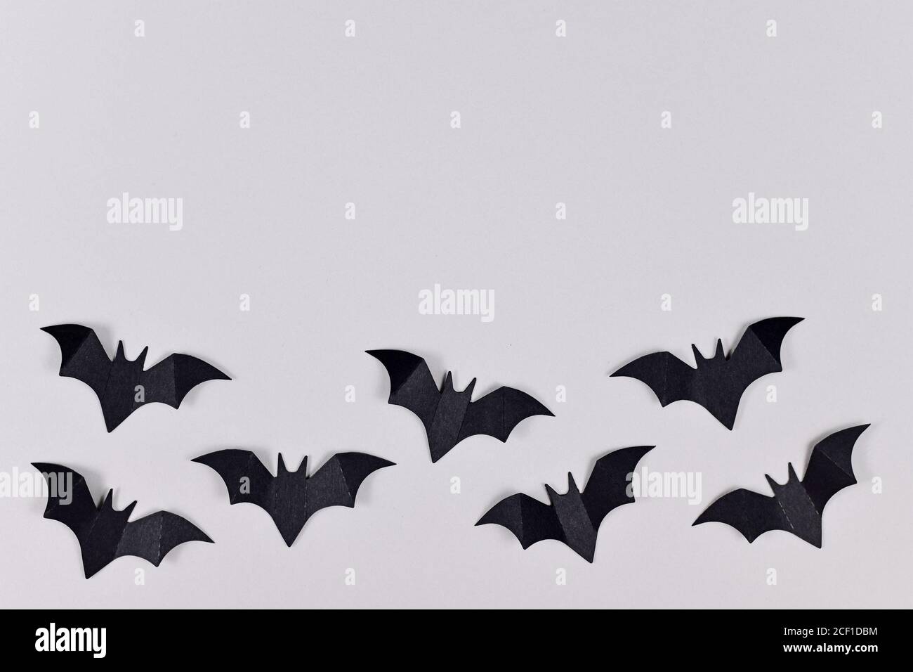 Black papercraft flying Halloween bats at bottom of gray background ...