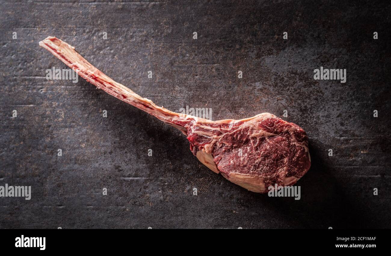 Raw tomahawk steak on a old rustic board - Top of view. Stock Photo