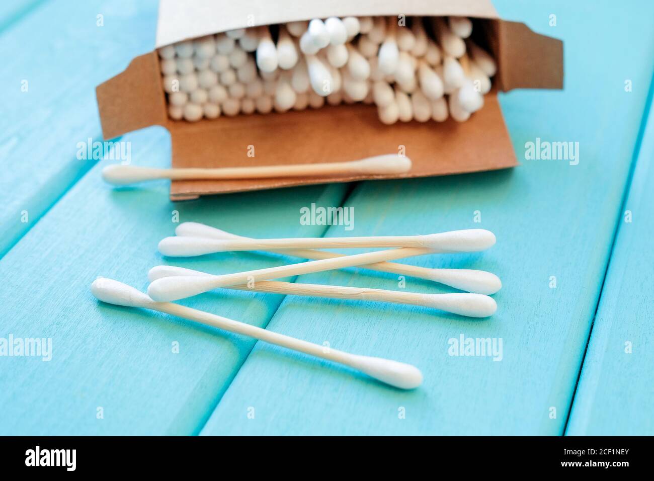 Cotton buds are scattered on a turquoise background. Ecofriendly