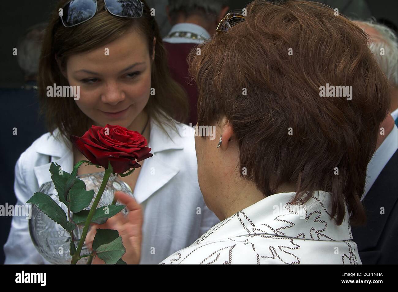 An adult daughter gives her mother a flower. Eine erwachsene Tochter gibt ihrer Mutter eine Blume.Una hija adulta le da una flor a su madre. Stock Photo