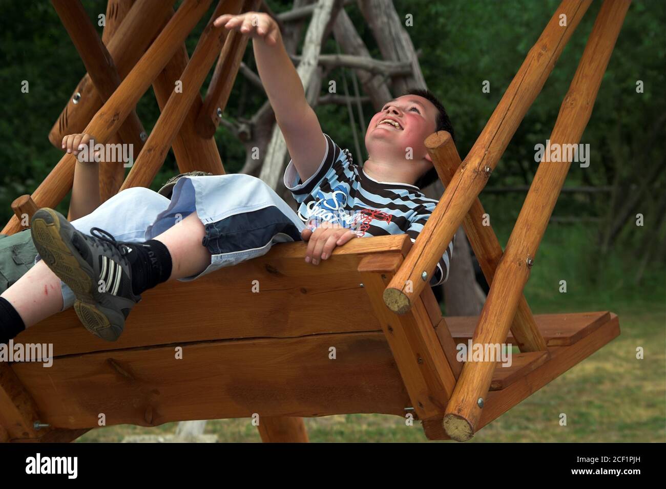 Smiling boy on a swing. Lächelnder Junge auf einer Schaukel. Niño sonriente en un columpio. Chłopiec na huśtawce. Stock Photo