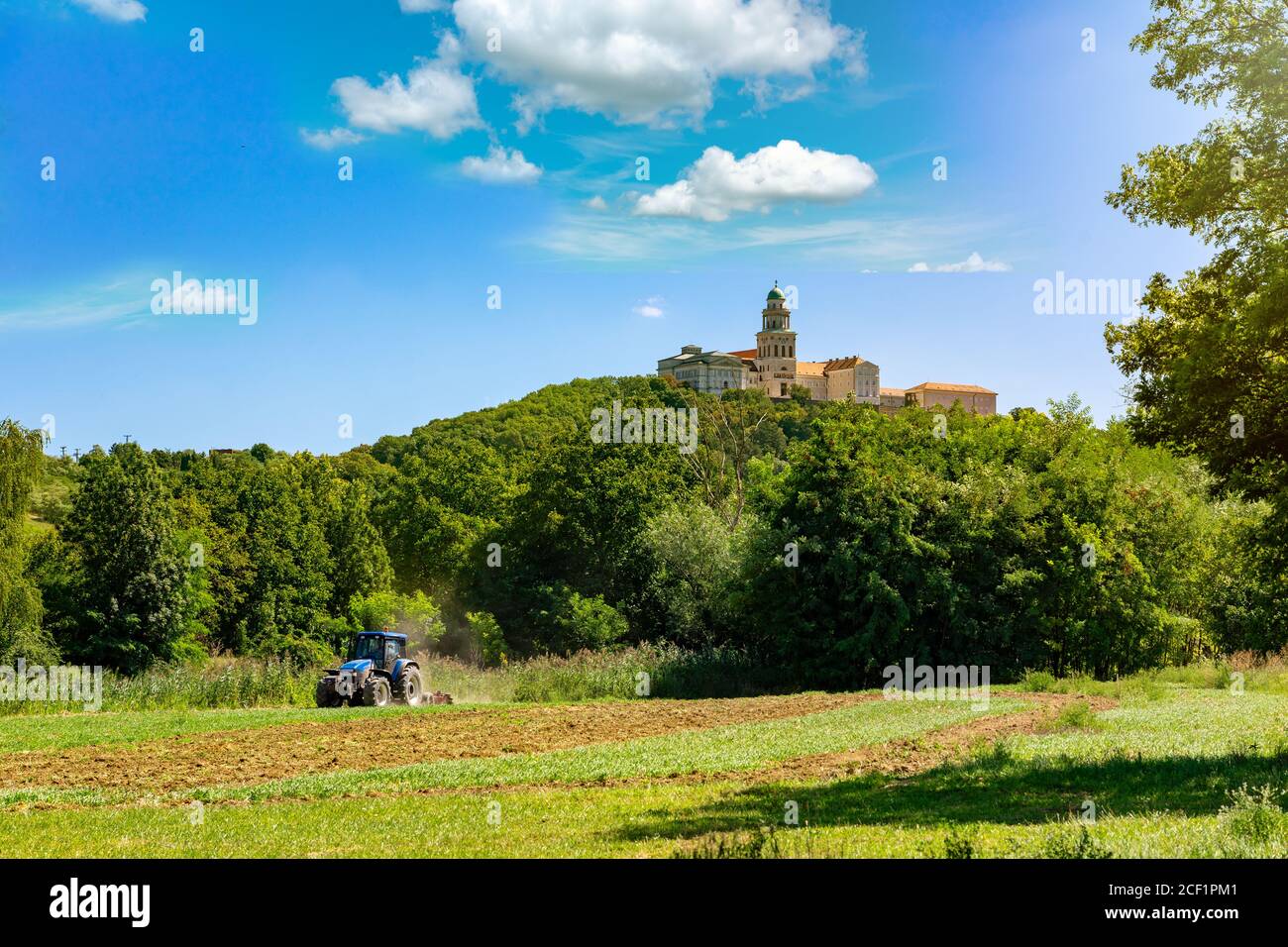 Pannonhalma abbey on the hill with agricultural field and tractor in summer Stock Photo