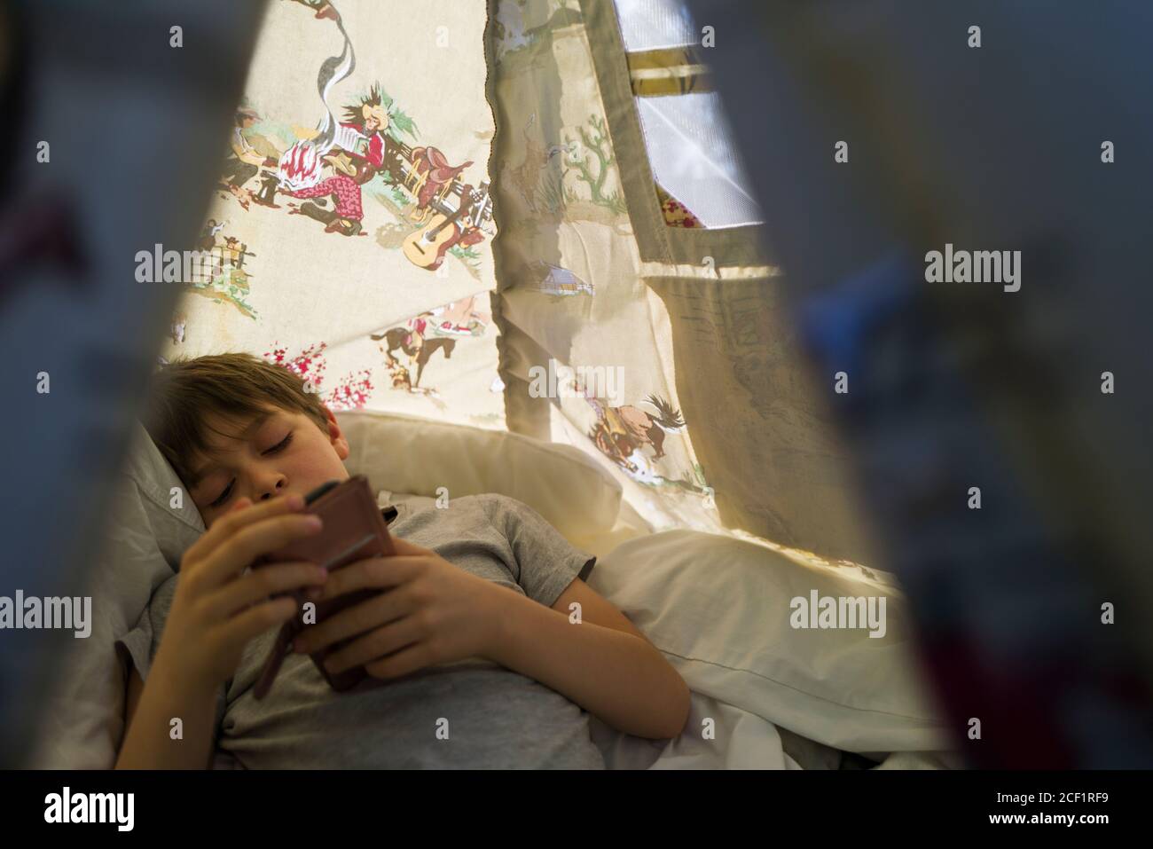 Boy using smart phone inside teepee Stock Photo