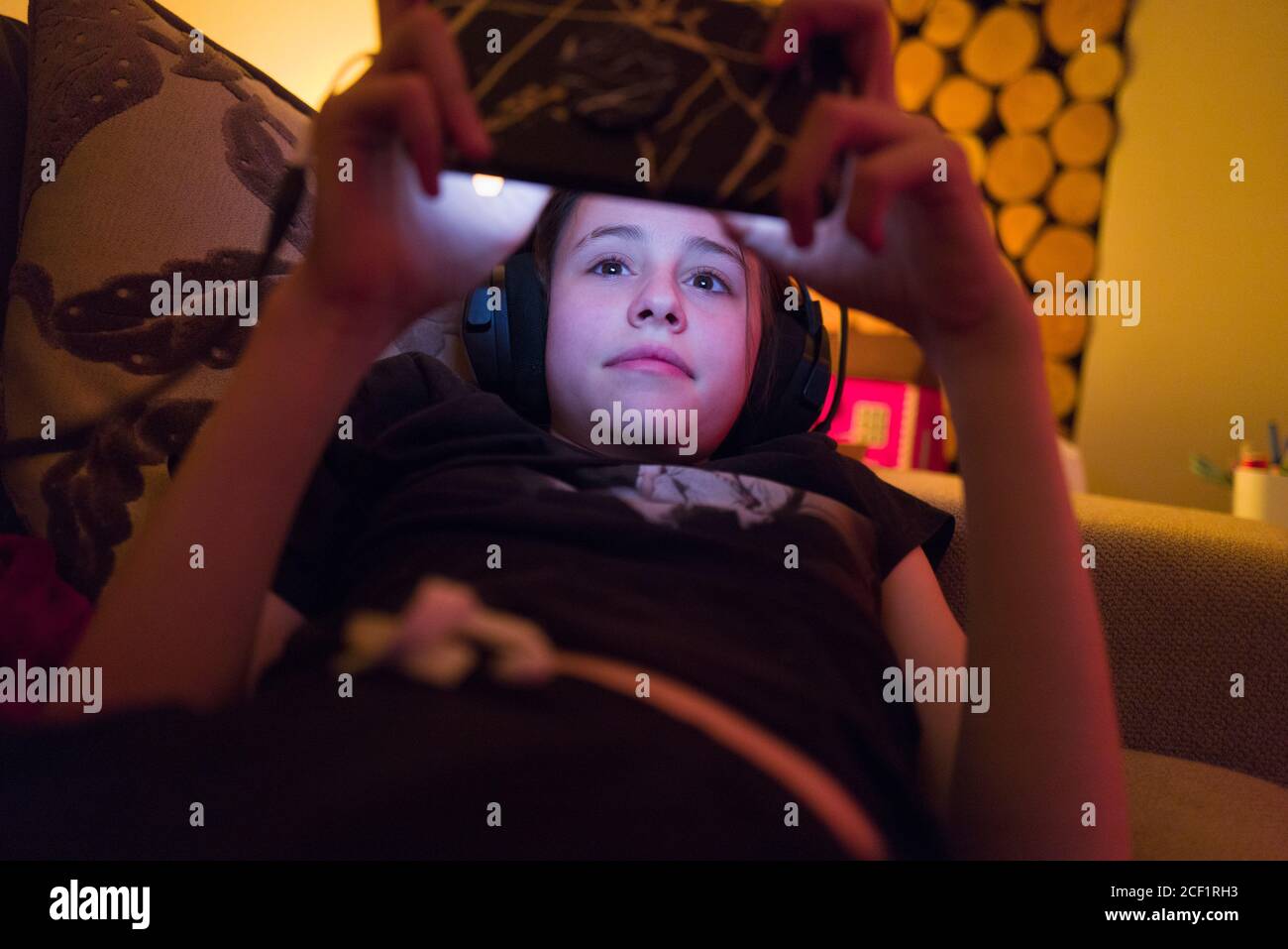 Girl with headphones using smart phone on sofa Stock Photo - Alamy