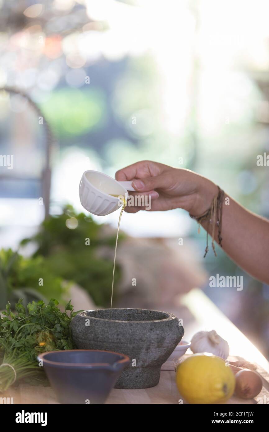 Woman cooking with olive oil and mortar in kitchen Stock Photo