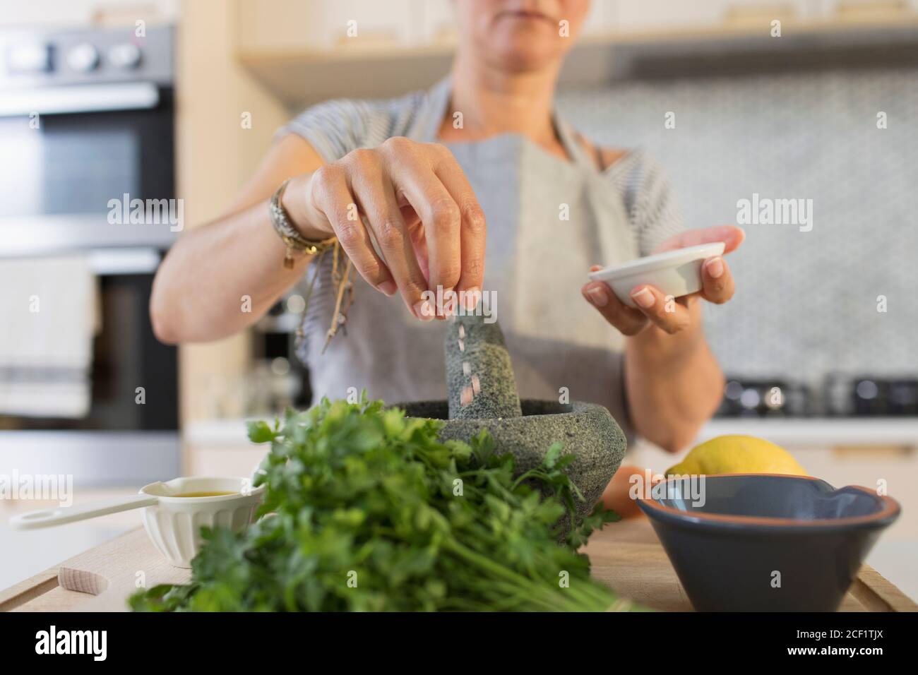 Woman cooking with mortar and pestle in kitchen Stock Photo