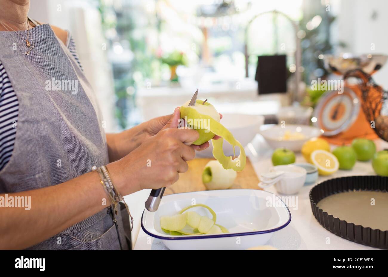 Close up woman slicing green apples for pie in kitchen Stock Photo