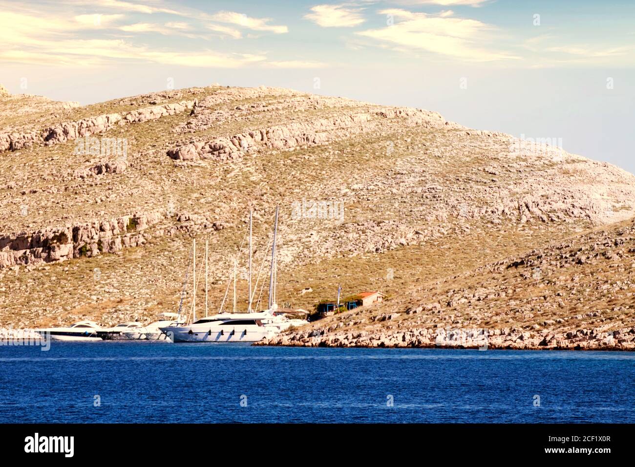 Boats moored at a small cove with a house on a island of the Kornati archipelago far from the Dalmatian cost of Croatia Stock Photo