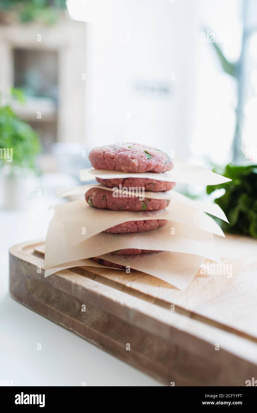 Raw hamburger patties stacked between parchment paper Stock Photo