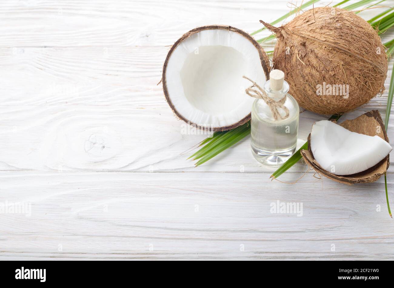 Coconut oil in glass jar and shell pieces on white wooden table Stock