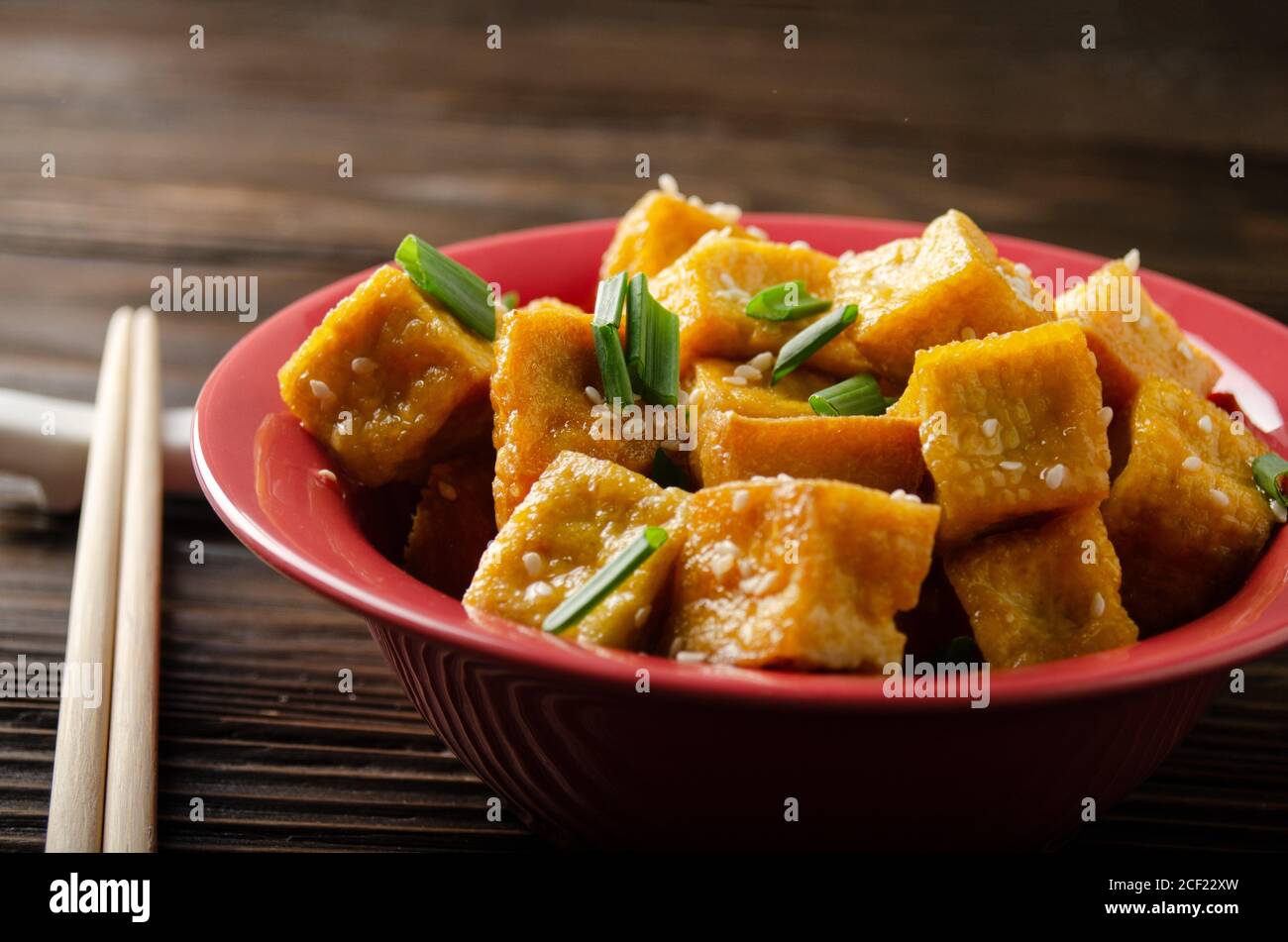 Crispy deep stir fried tofu cubes with chives in clay dish on wooden