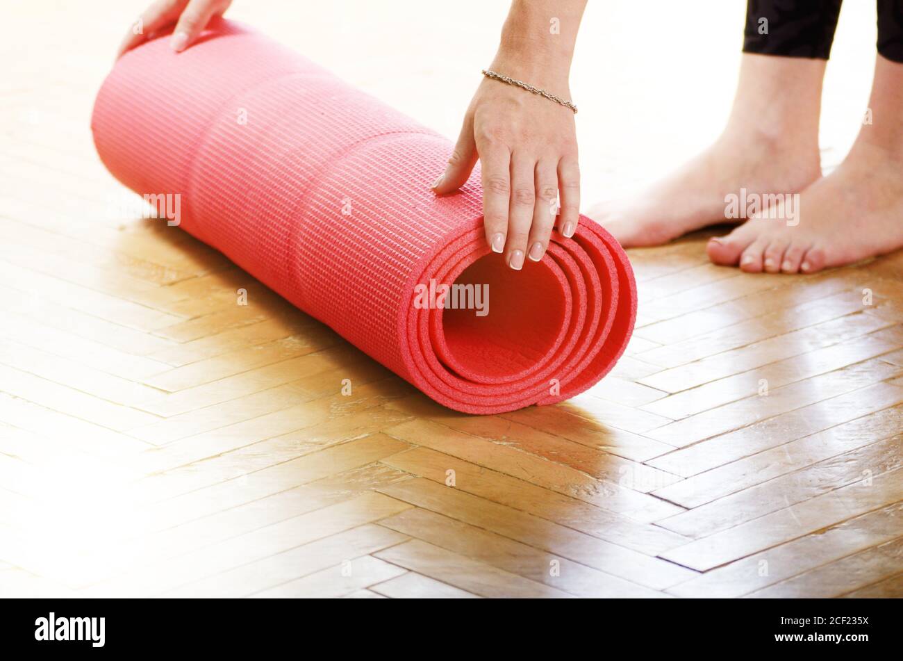 Female hands unrolling yoga mat before workout exercise. Healthy lifestyle concept. Stock Photo