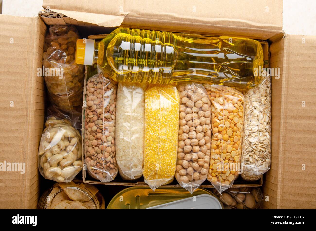 Flat lay view at uncooked foods in carton box prepared for disaster emergency conditions or giving away. Stock Photo
