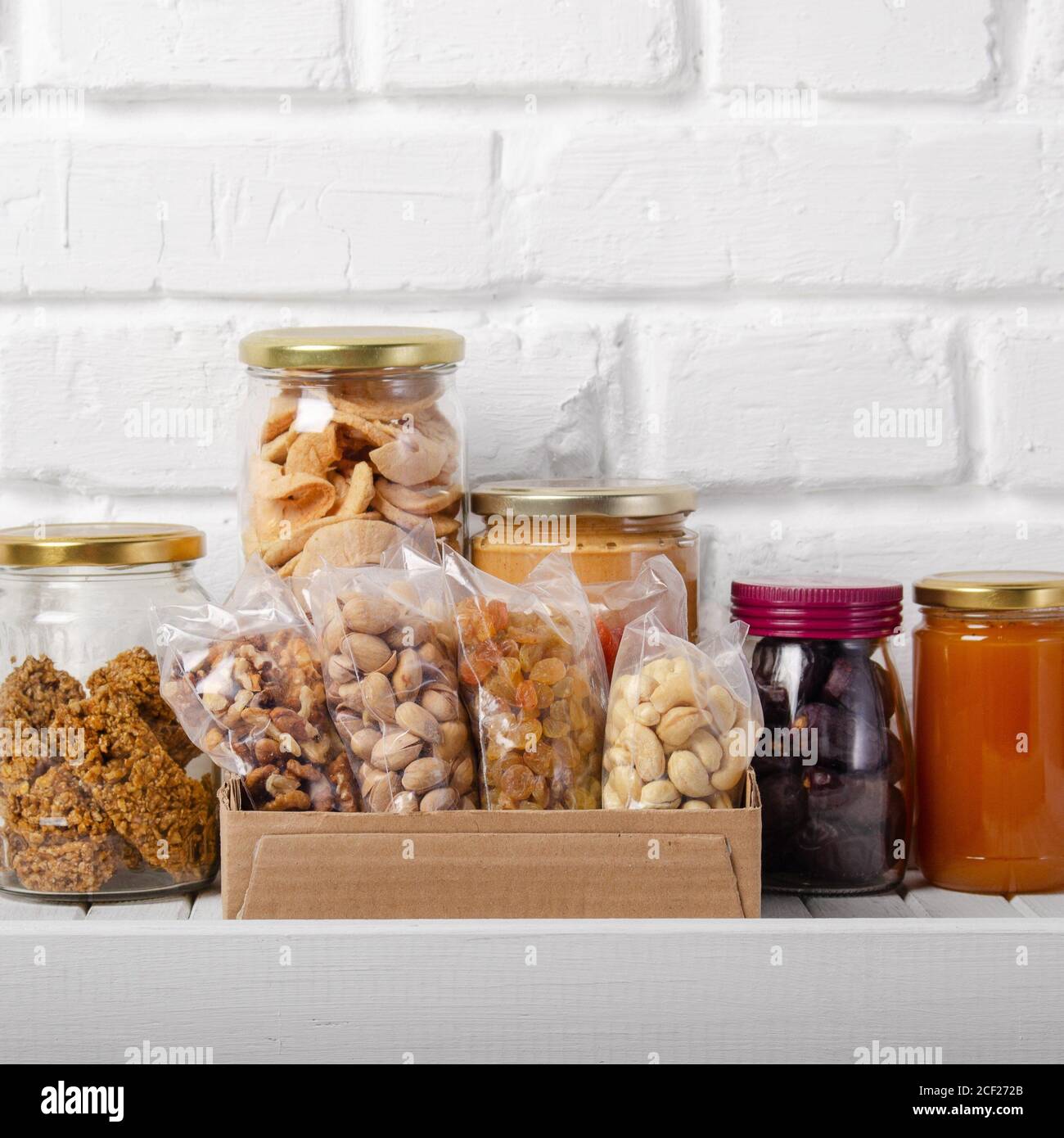 Set of long storage term mostly dry sweet energy foods on pantry shelf on brick wall background. Stock Photo