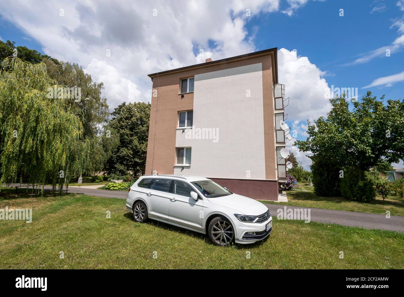 white VW Passat combi in front of block of flats in sunny day Stock Photo