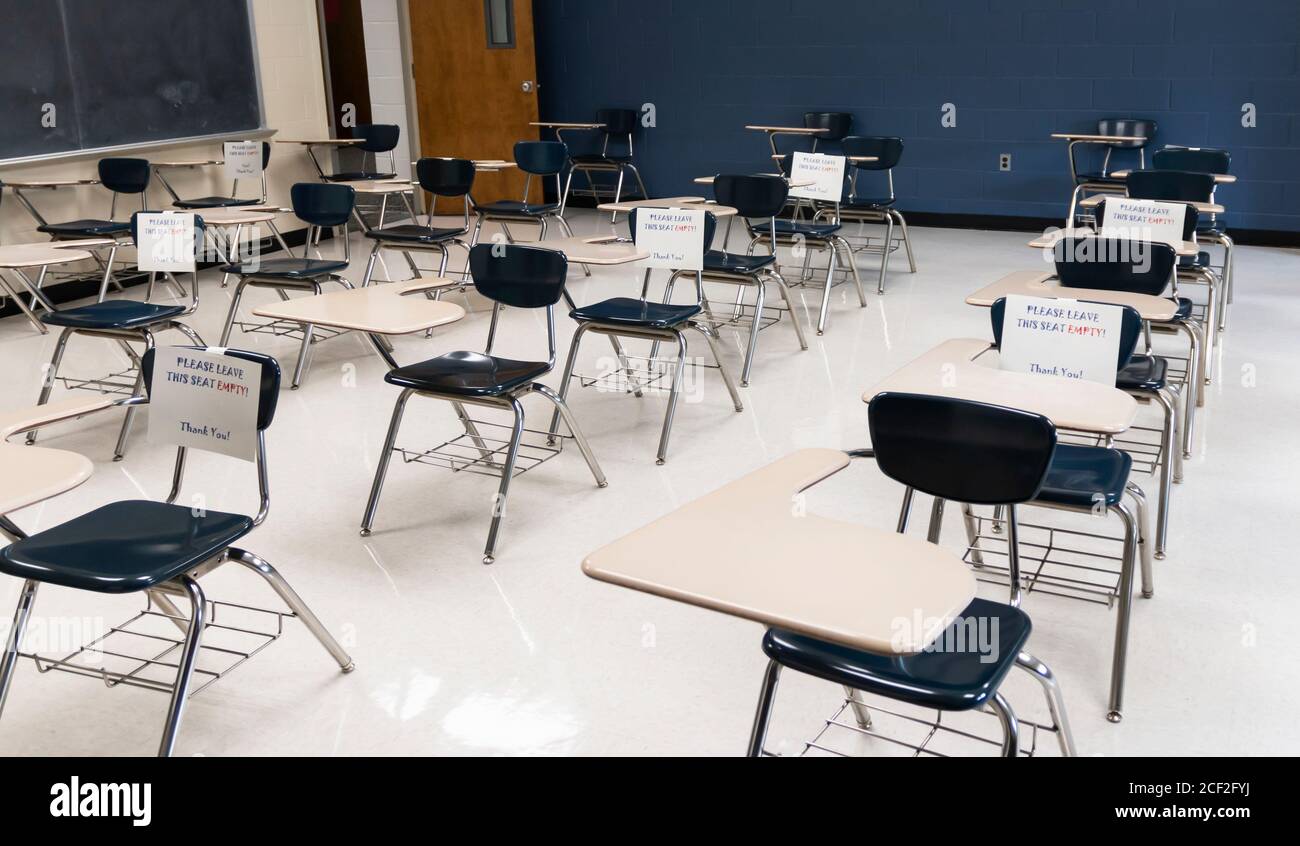 Desks in a high school classroom have sign reading fo not sit leave empty  to help