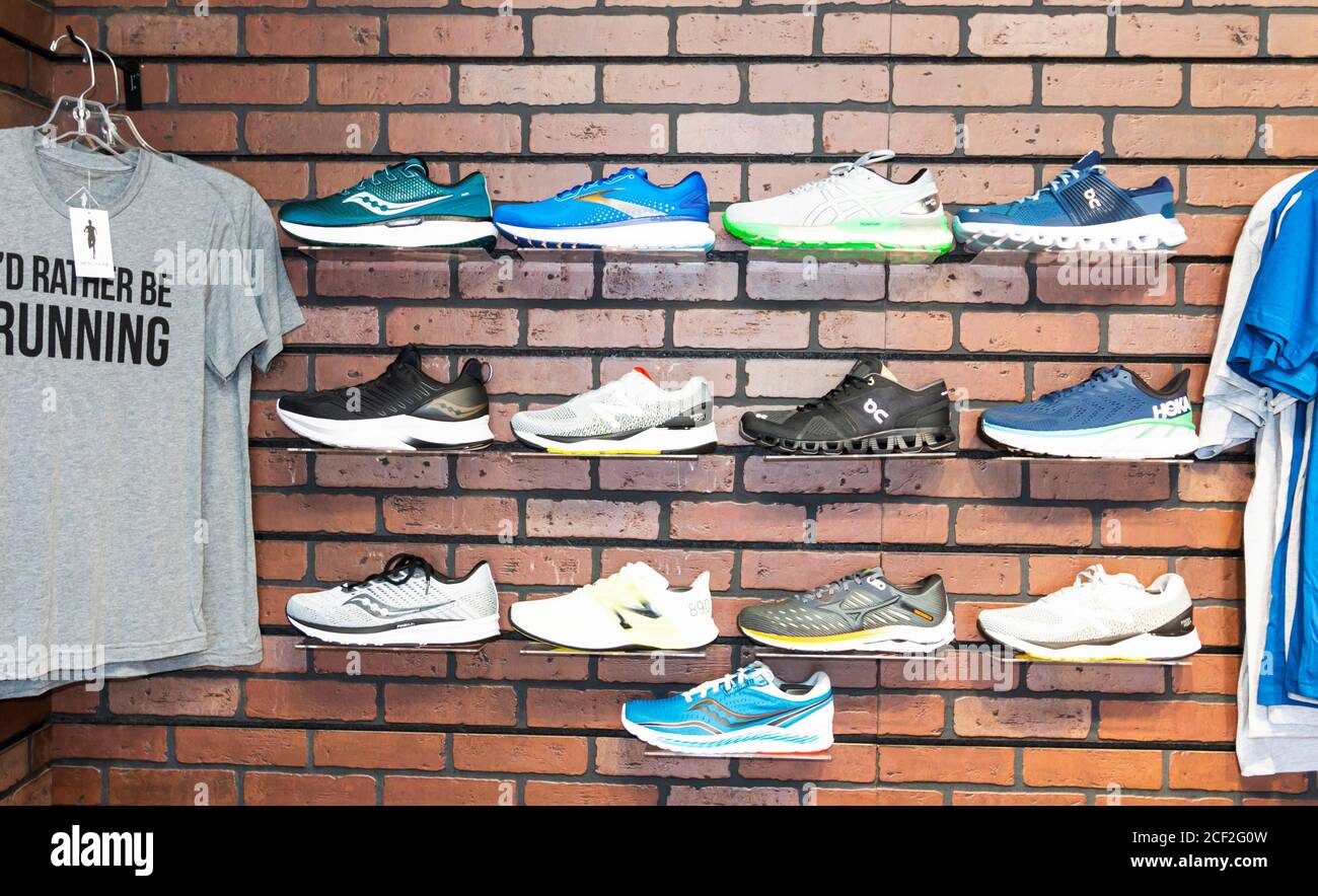 Smithtown, New York, USA - 28 August 2020: The wall of a running shoe specialty store has different brands of shoes displayed on the wall next to some Stock Photo