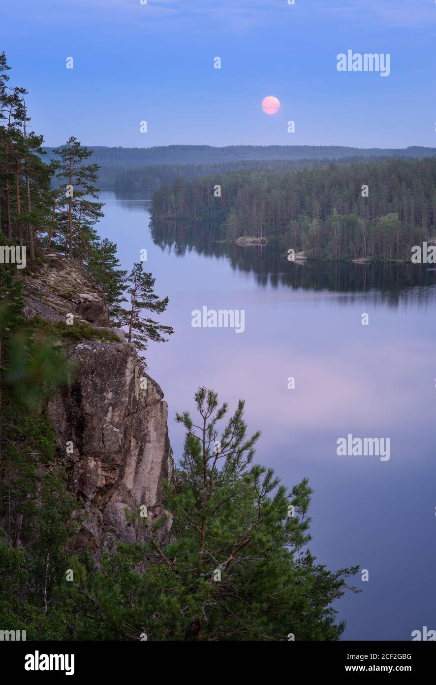 Mood moonlight landscape with calm forest and lake at summer night in Finland Stock Photo