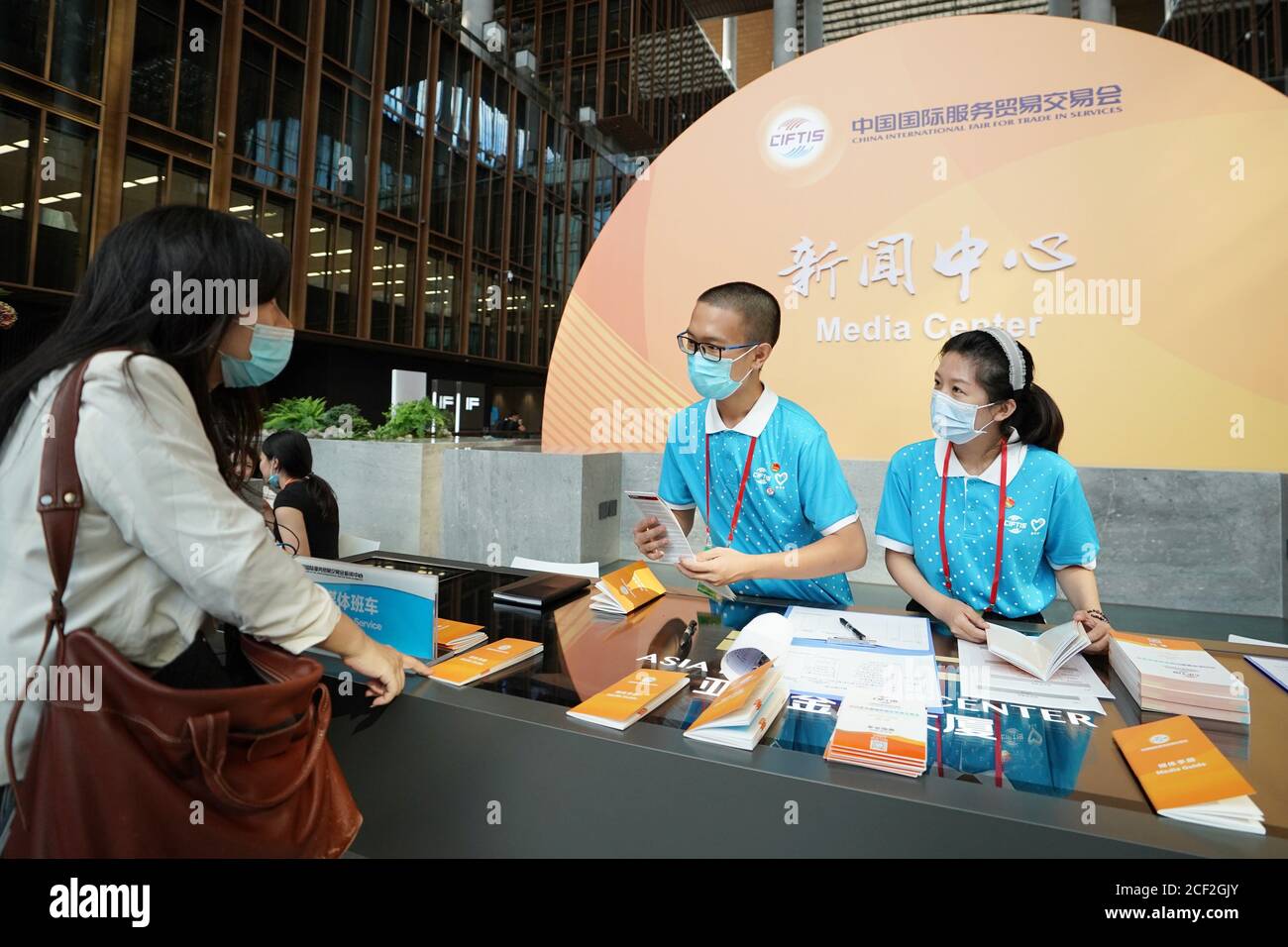 Beijing, China. 3rd Sep, 2020. Volunteers talk with a journalist at the media center of the China International Fair for Trade in Services (CIFTIS) in Beijing, capital of China, Sept. 3, 2020. The media center of the CIFTIS started trial operation on Thursday. The CIFTIS is to be held from Sept. 4 to 9. Credit: Ju Huanzong/Xinhua/Alamy Live News Stock Photo