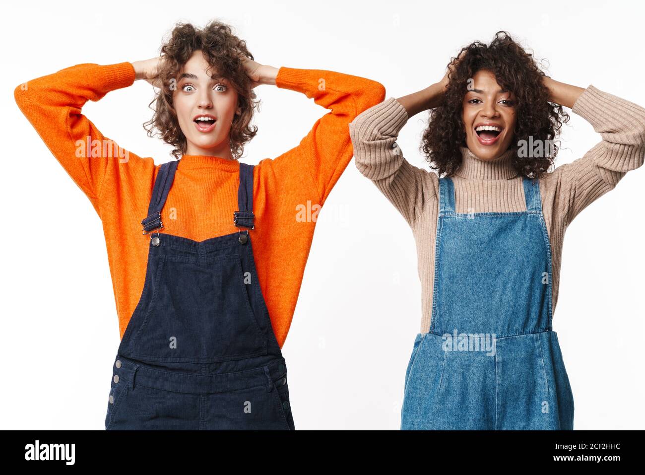 Portrait of delighted multinational women in overalls smiling and ...
