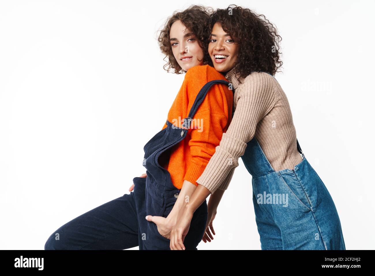 Portrait of joyful multinational women in overalls looking at camera ...