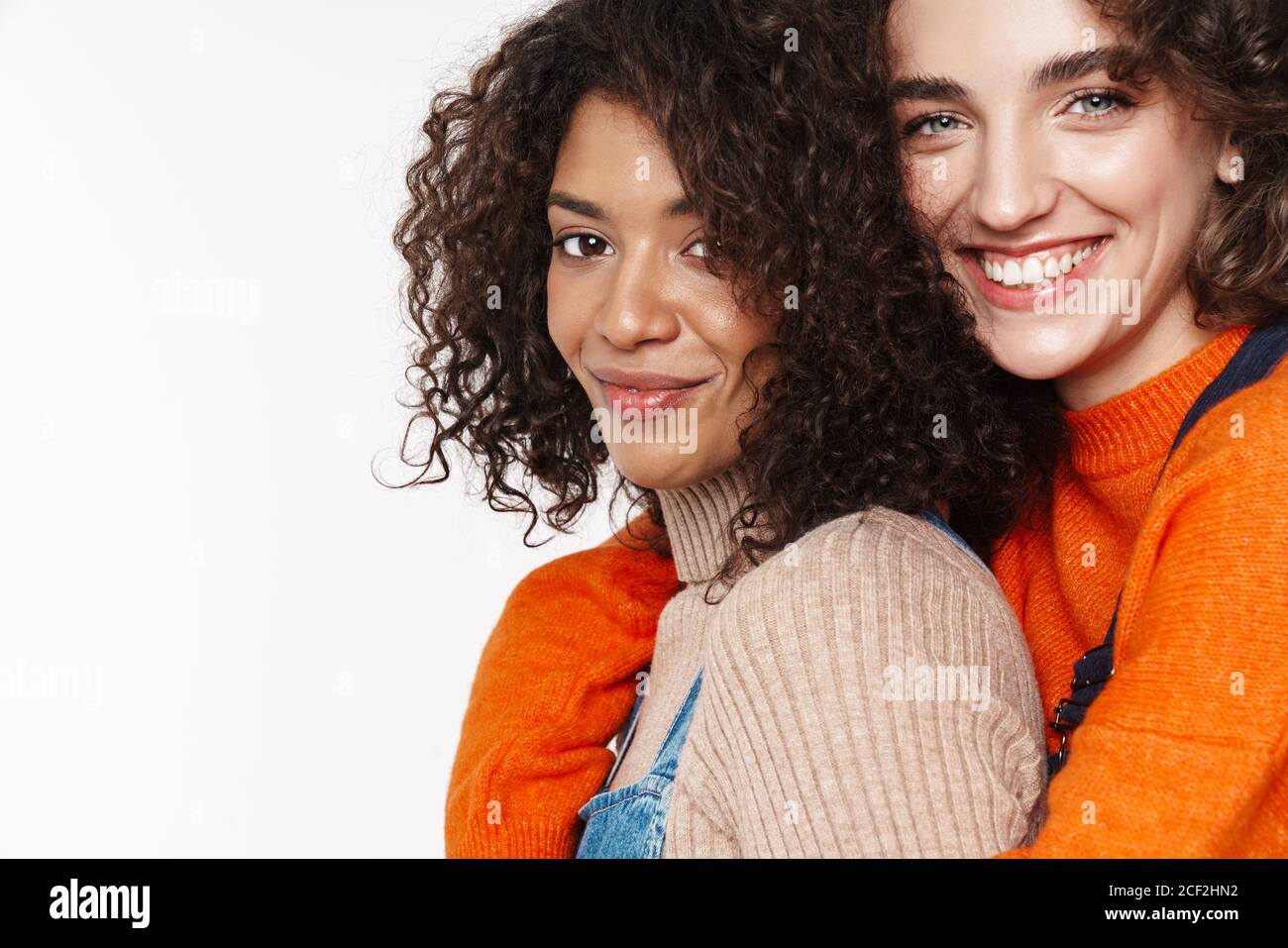 Portrait of cheerful multinational women in overalls smiling and ...