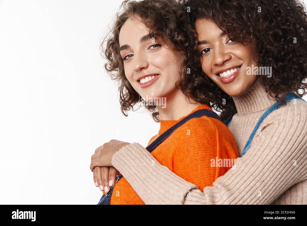 Portrait of cheerful multinational women in overalls smiling and ...