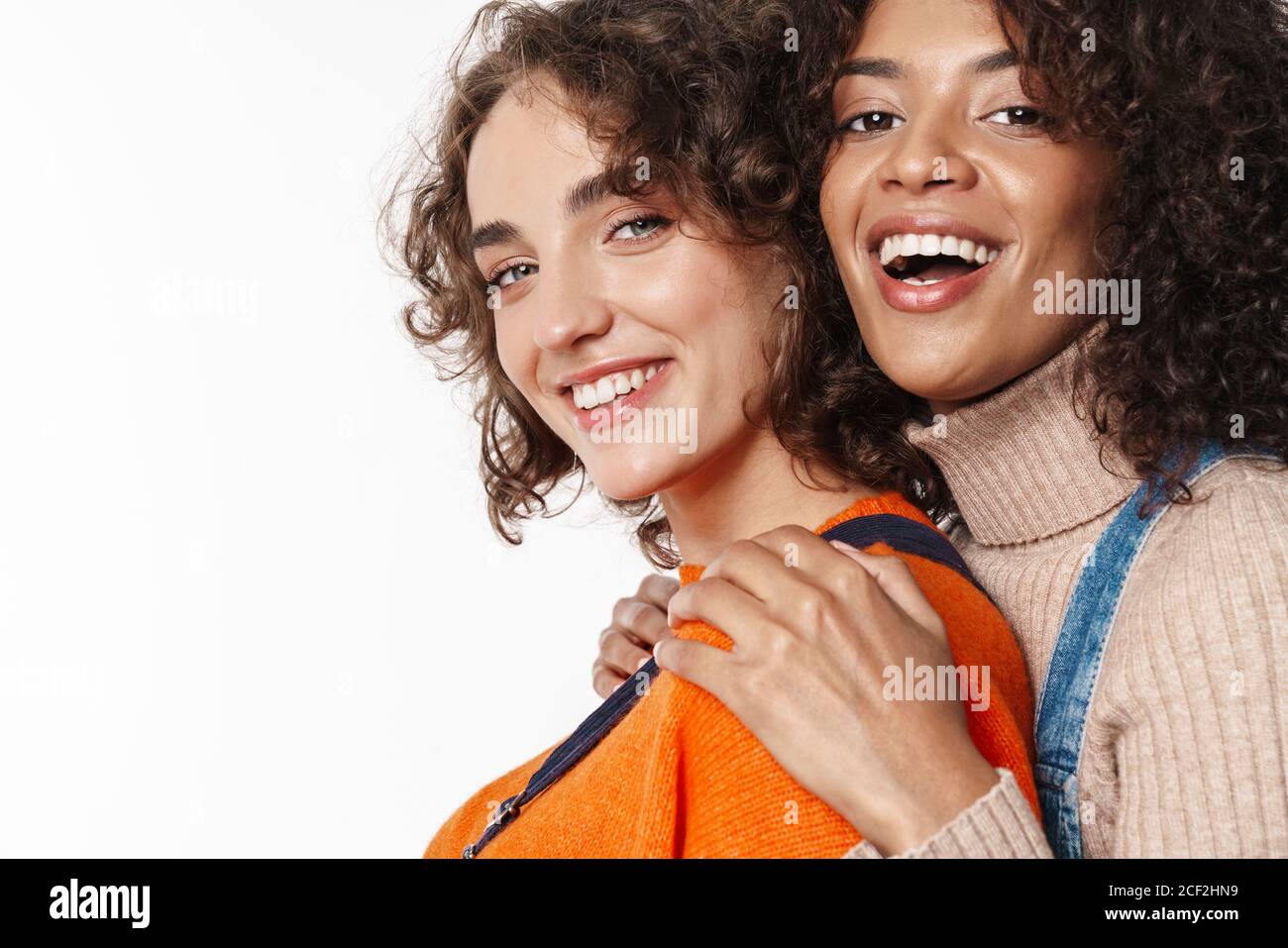 Portrait of cheerful multinational women in overalls laughing and ...
