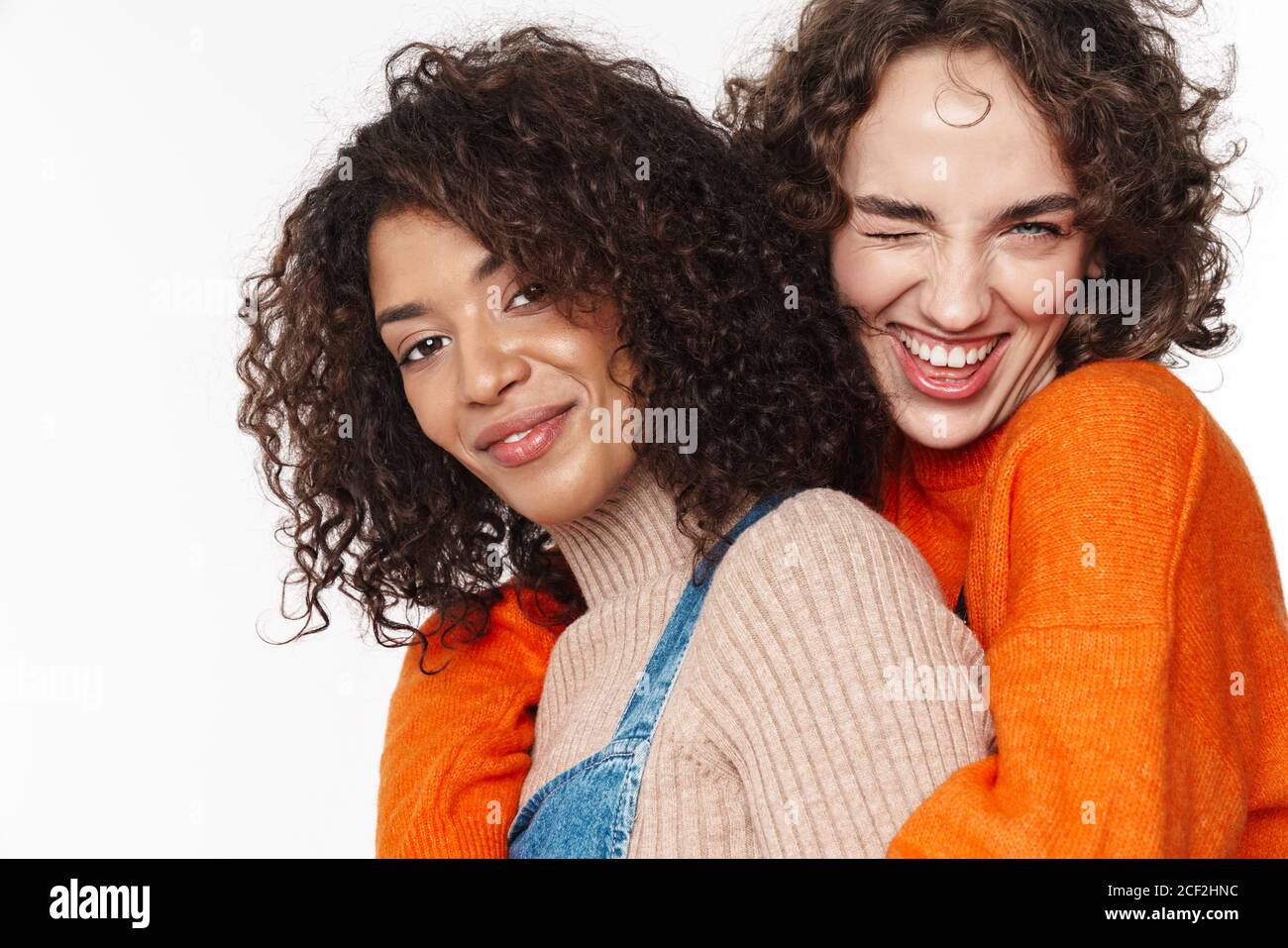 Portrait of cheerful multinational women in overalls winking and ...