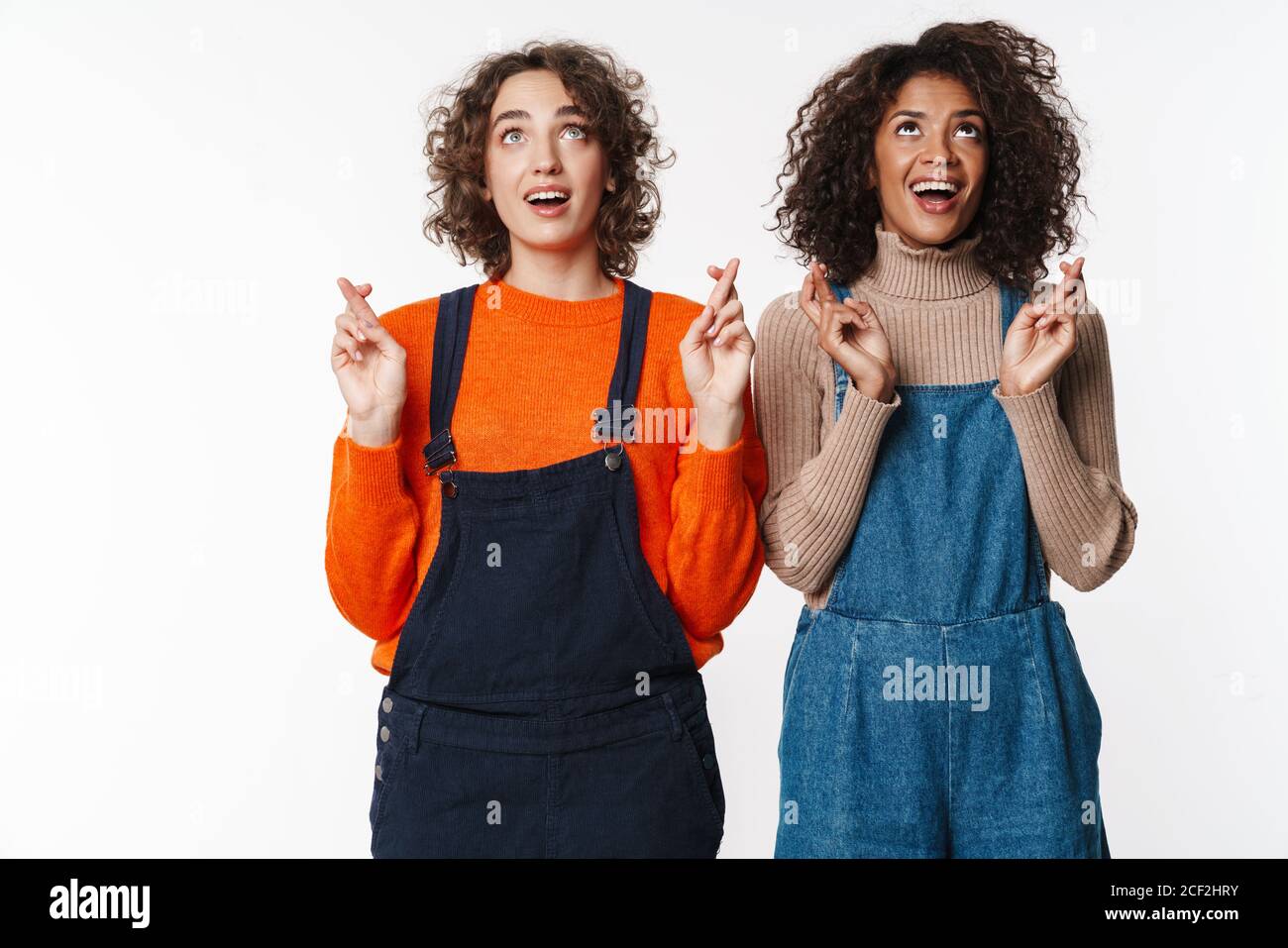 Portrait of excited multinational women in overalls looking upward with ...