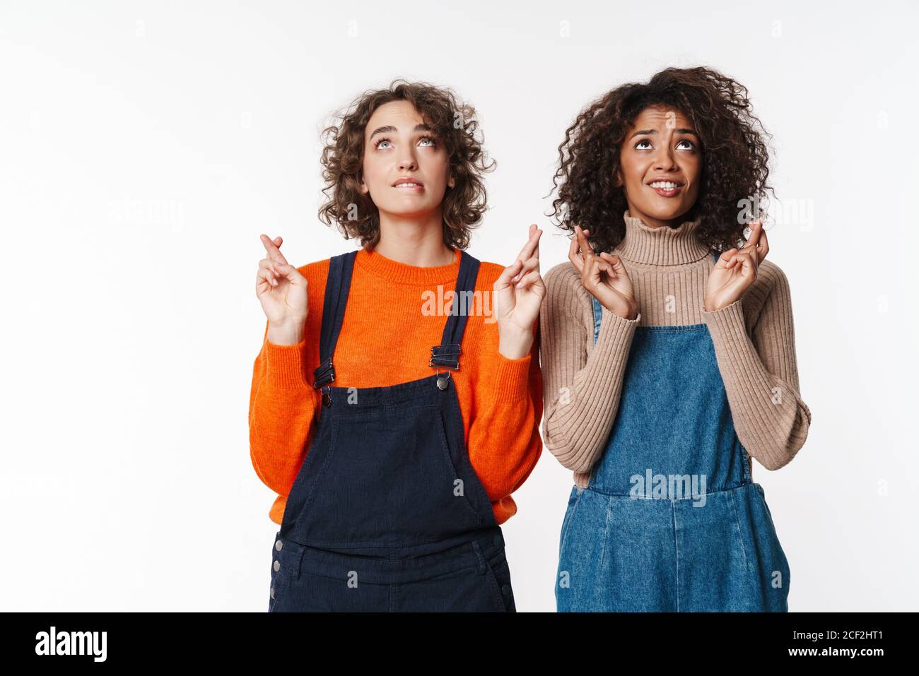 Portrait of cute multinational women in overalls looking upward with ...
