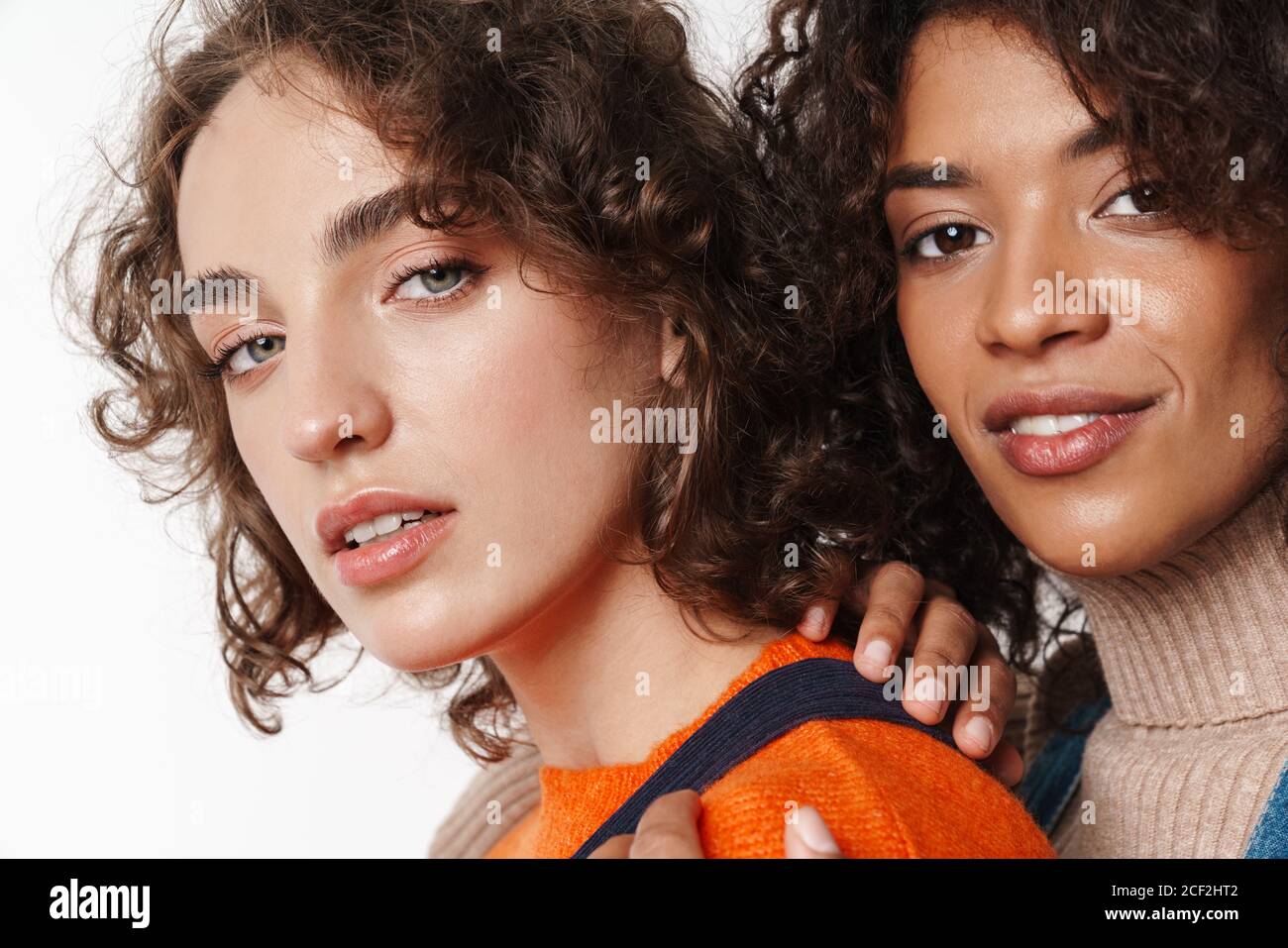 Portrait of pretty multinational women in overalls looking at camera ...