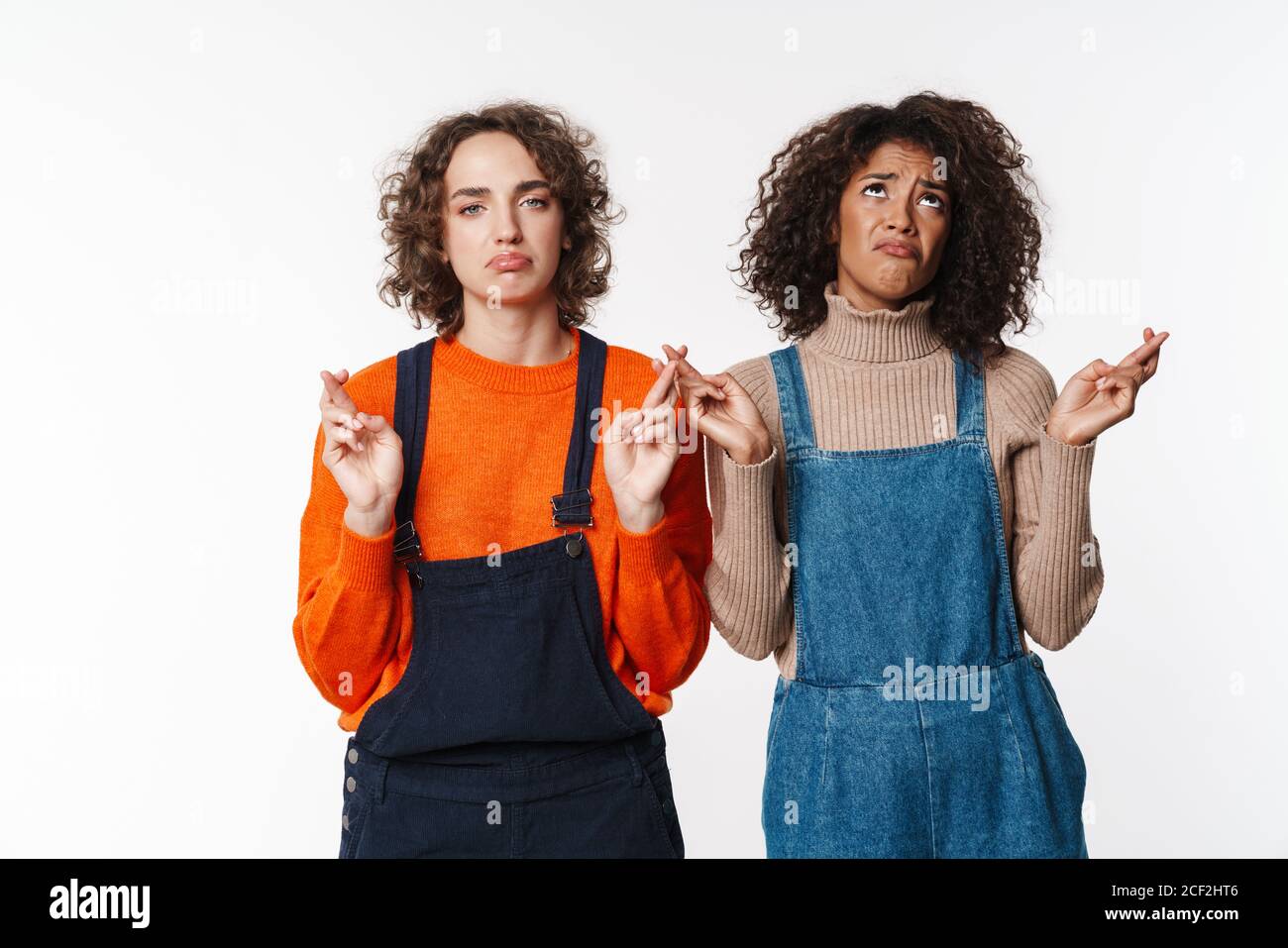 Portrait of unhappy multinational women in overalls looking at camera ...