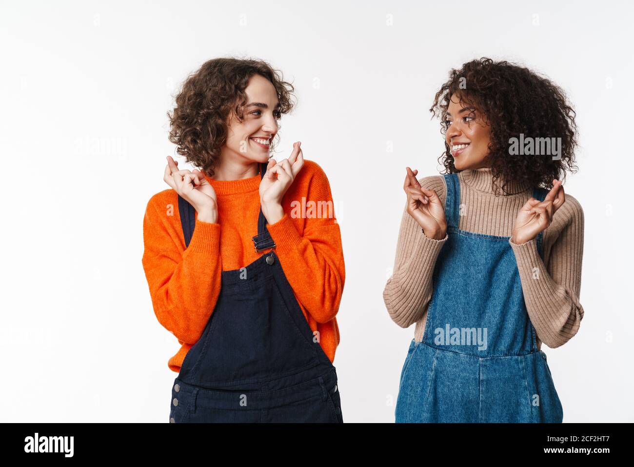 Portrait of happy multinational women in overalls looking at each other ...