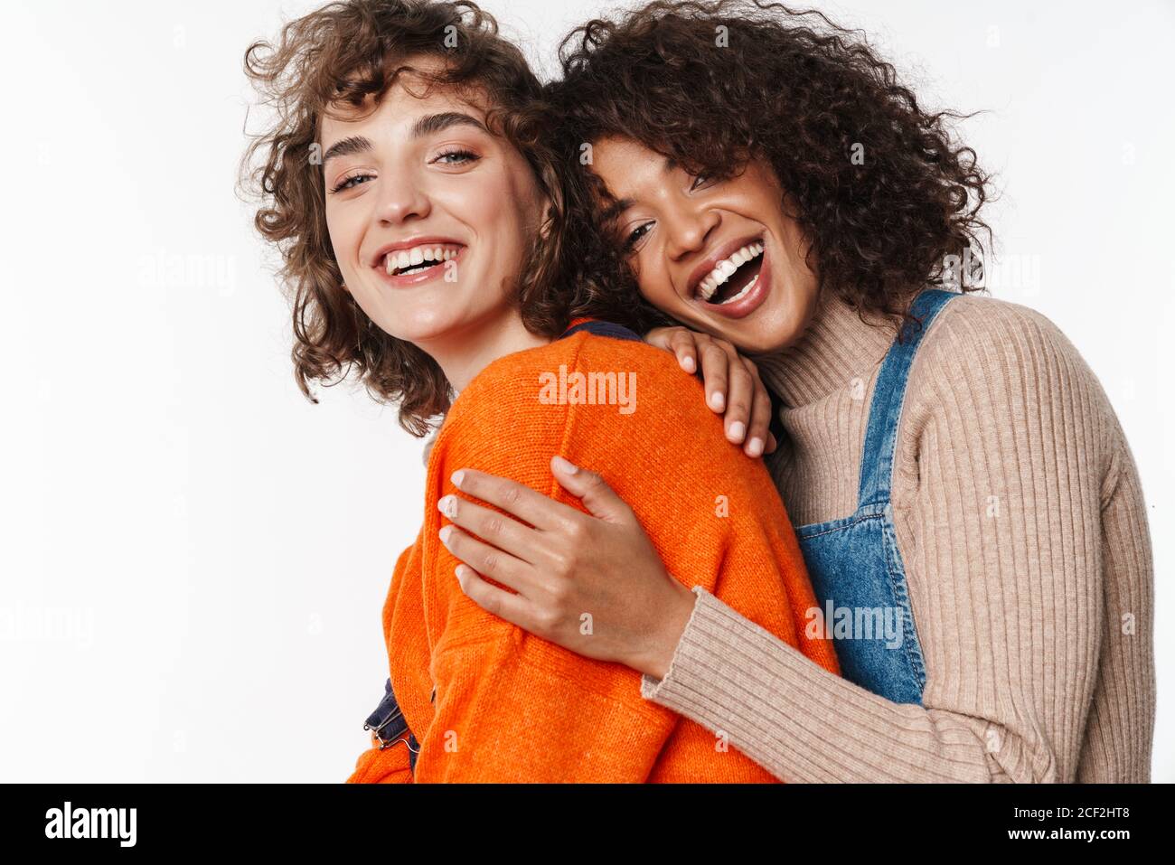 Portrait of excited multinational women in overalls laughing and ...