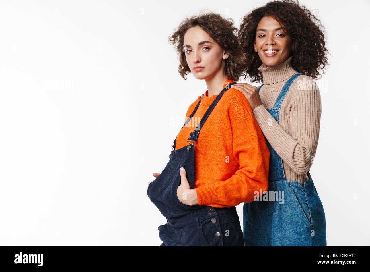 Portrait of lovely multinational women in overalls looking at camera ...