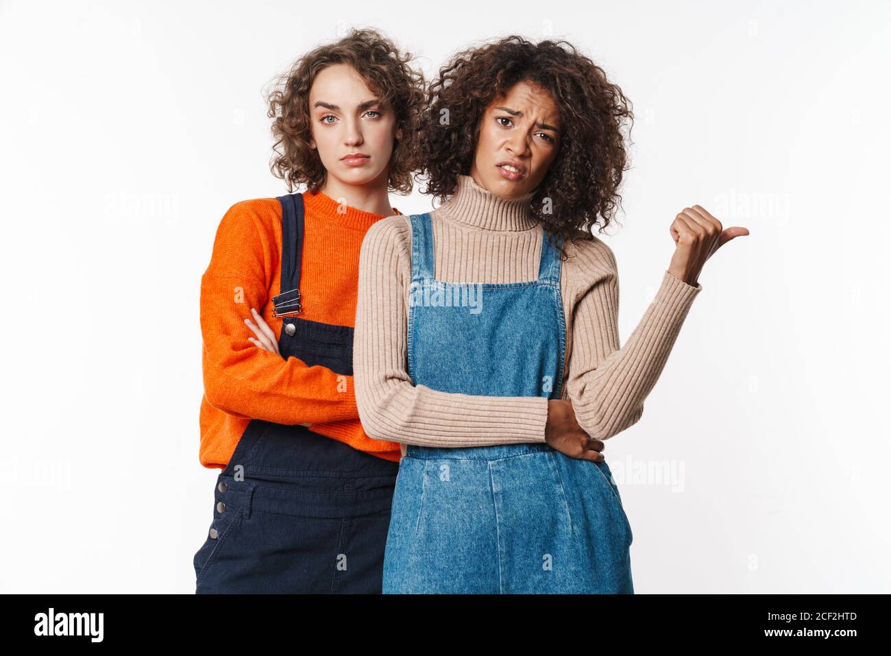 Portrait of displeased multinational women in overalls looking at ...