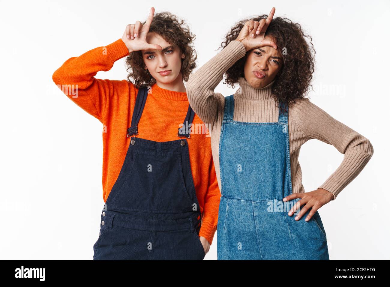 Portrait of unhappy multinational women in overalls looking at camera ...