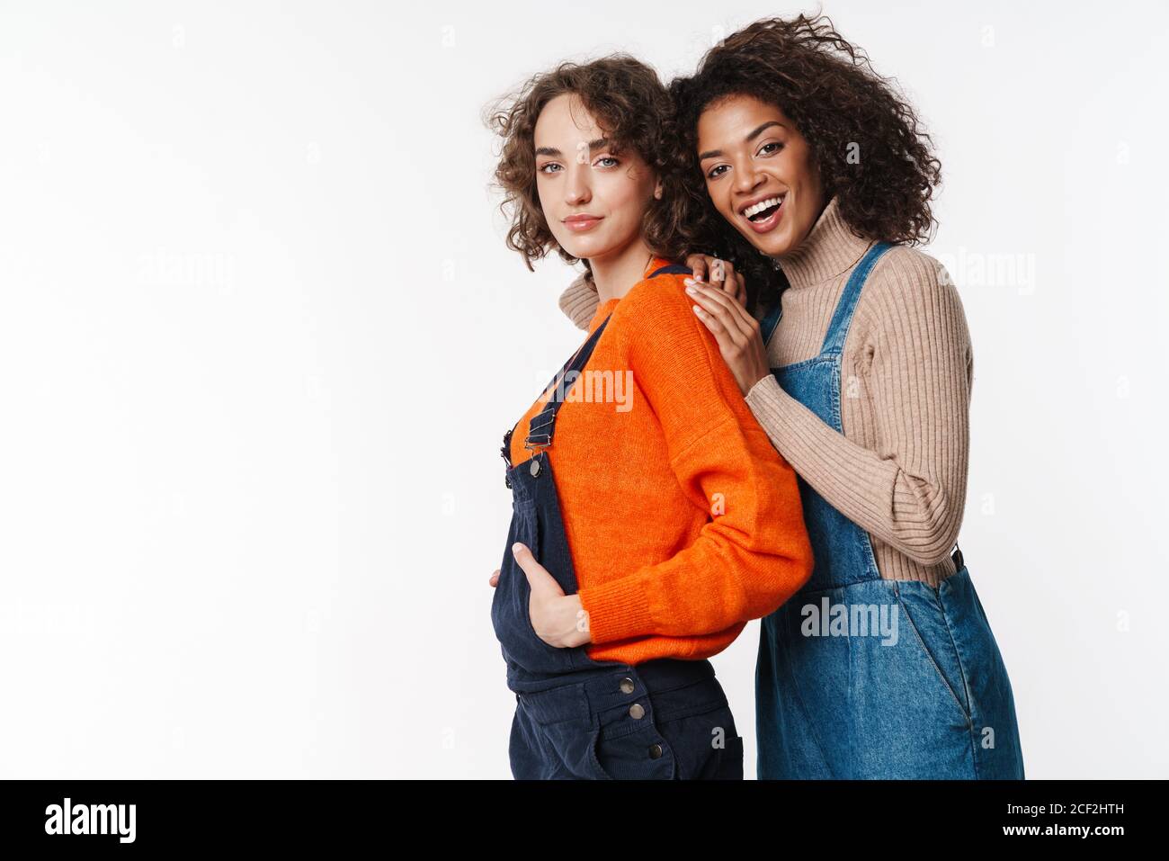 Portrait of happy multinational women in overalls looking at camera and ...