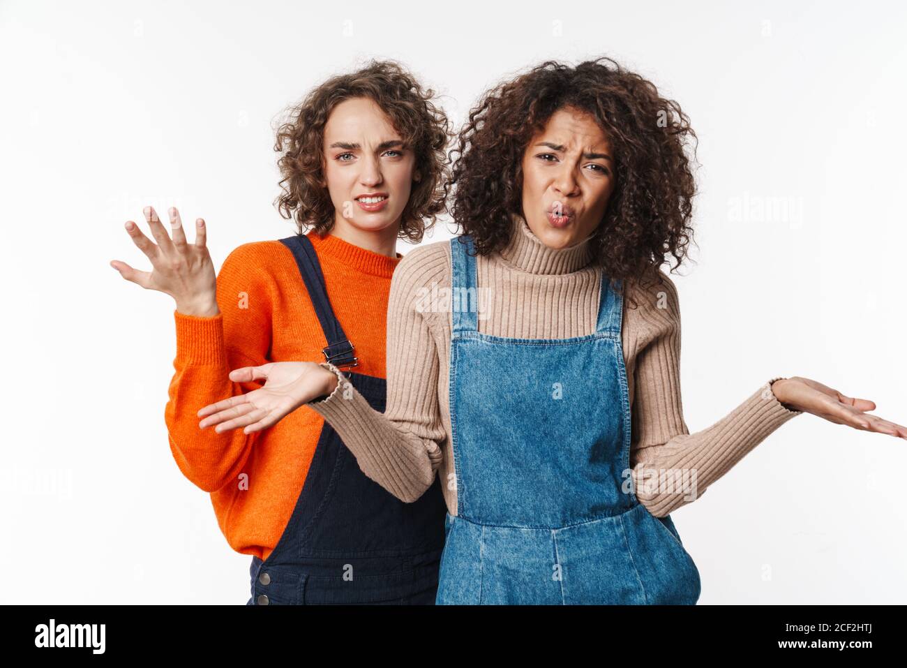 Portrait of annoyed multinational women in overalls looking at camera ...