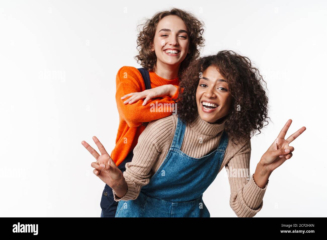 Portrait of joyful multinational women in overalls making fun and ...