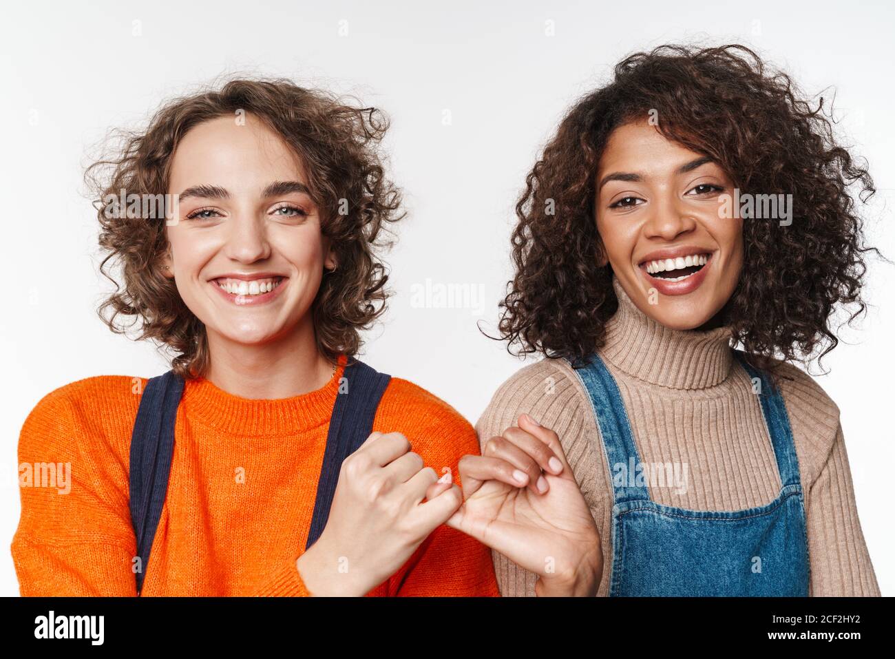 Portrait of beautiful multinational women in overalls smiling and ...