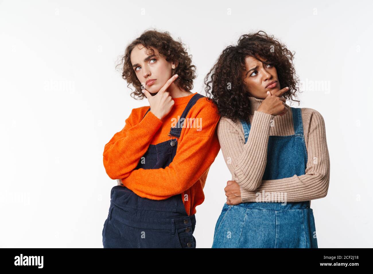 Portrait of displeased multinational women in overalls thinking and ...