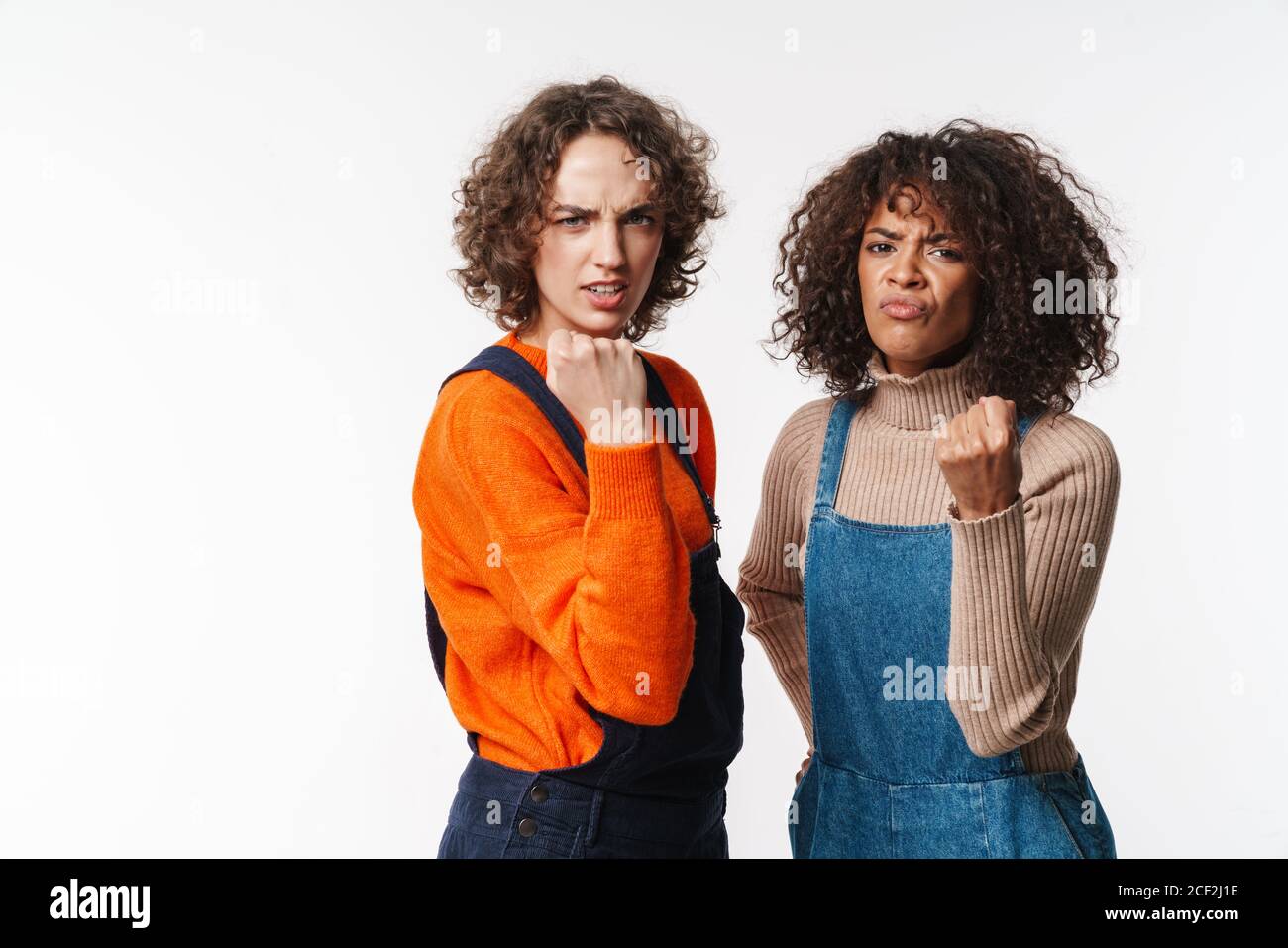 Portrait of angry multinational women in overalls showing fists at ...