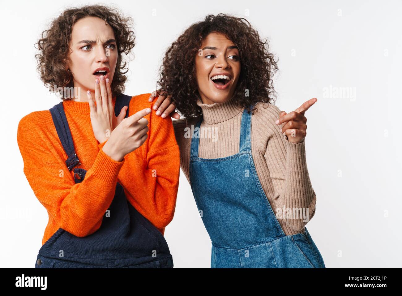 Portrait of shocked multinational women in overalls pointing fingers ...