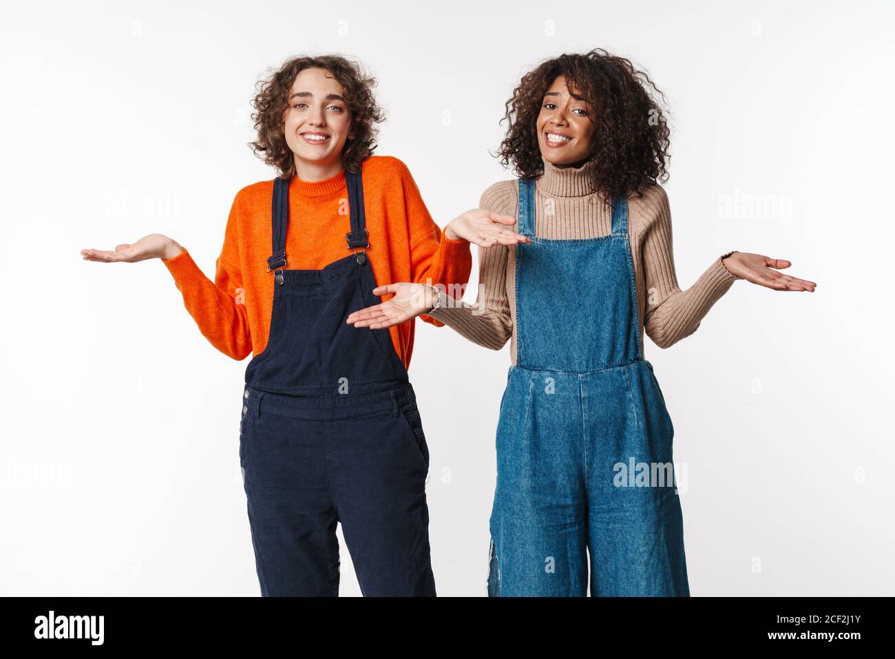 Portrait of nice multinational women in overalls looking at camera and ...