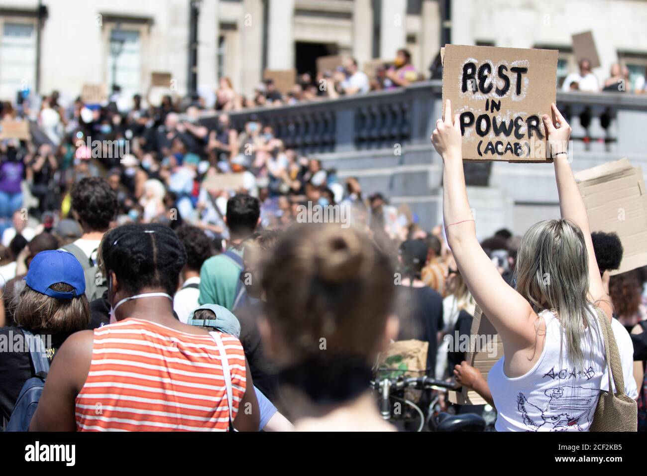 A white female protester holds a sign saying Rest In Power at a Black Lives Matter protest in Trafalgar Square, London Stock Photo