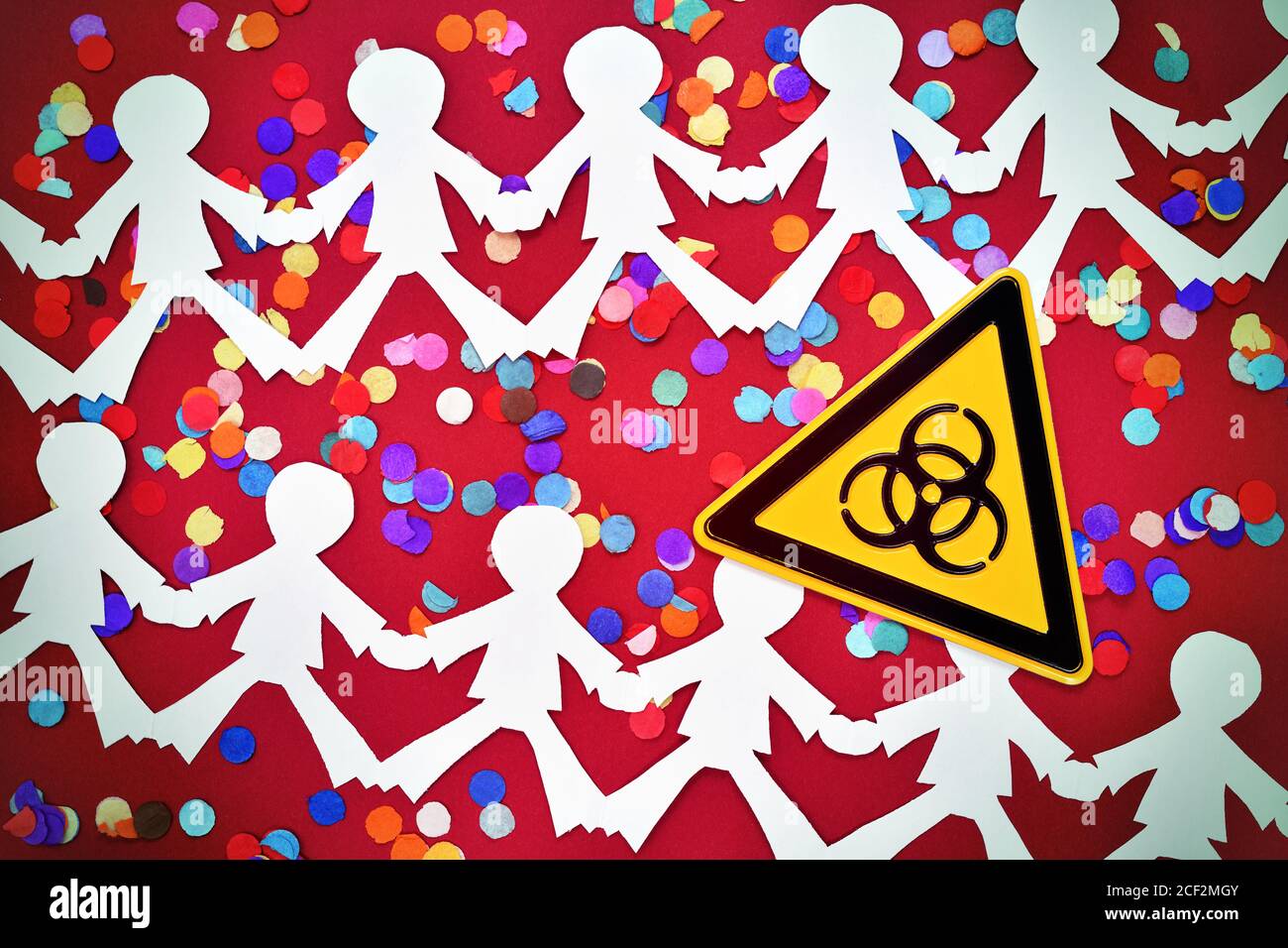 Chain of people, confetti and biohazard sign, corona infections at events Stock Photo