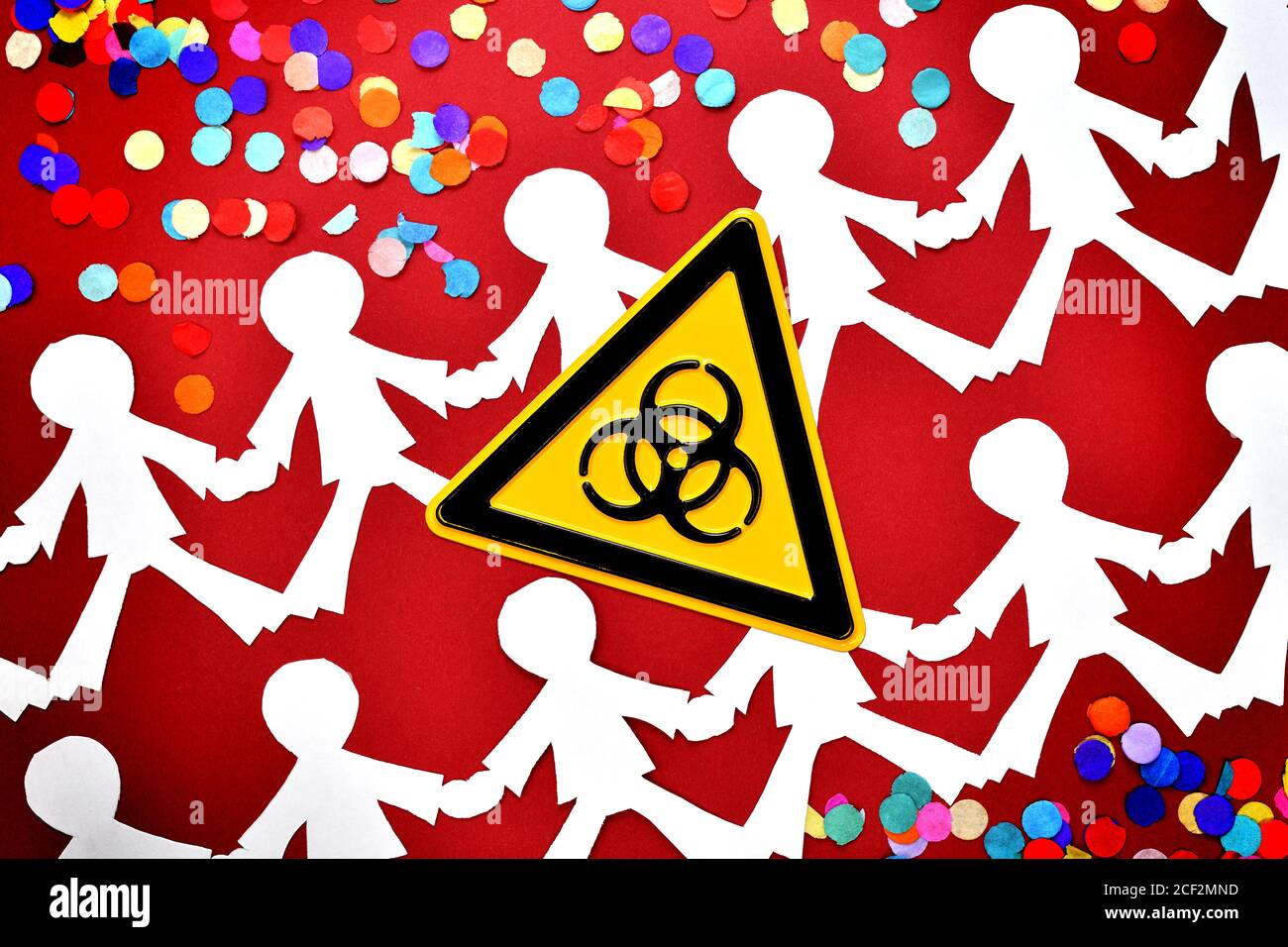 Chain of people, confetti and biohazard sign, corona infections at events Stock Photo