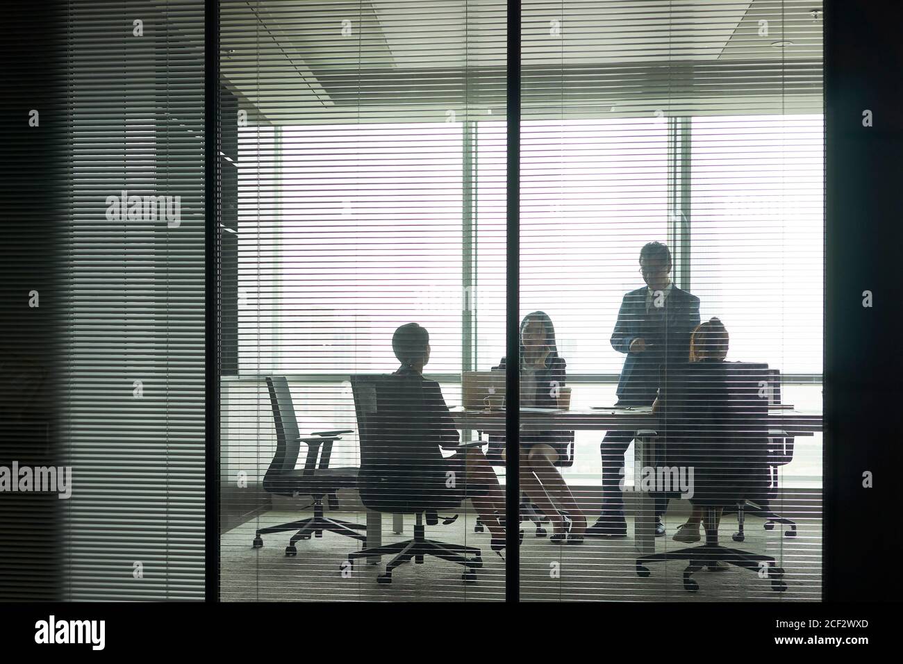 through-the-glass shot of a group of business people meeting in conference room Stock Photo